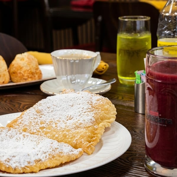 A table laden with a breakfast spread including pastries, coffee, juice, and a berry smoothie.